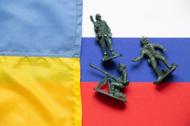 The flag of Ukraine and Russia and on the Russian flags are scattered plastic soldiers for children, the Ukrainian-Russian war