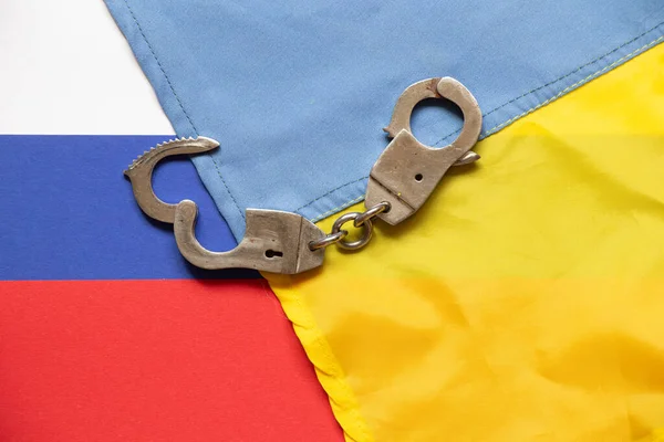 Ukrainian and Russian flags and handcuffs lie in the middle, law and justice