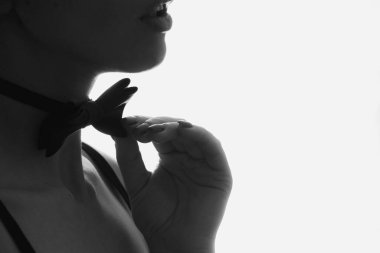 A girl with a butterfly bow around her neck in the dark, black and white photo, a butterfly bow around her neck