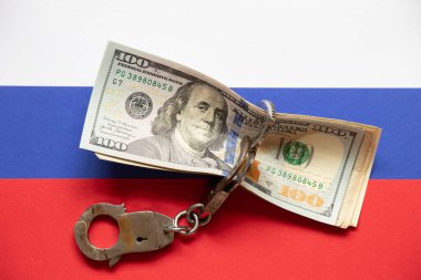 American dollars in handcuffs against the background of the flag of Russia, sanctions in Russia, business and finance, the aggressor country