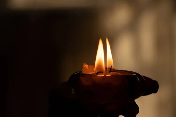 A woman\'s hand holds a burning candle in the dark, candle flame and religion, prayer and candle