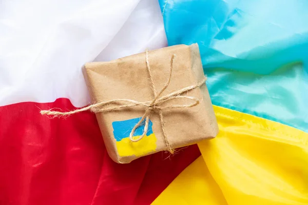 A paper box with a painted flag of Ukraine lies on the flags of Poland and Ukraine , humanitarian aid and support for Ukraine, postage and mail