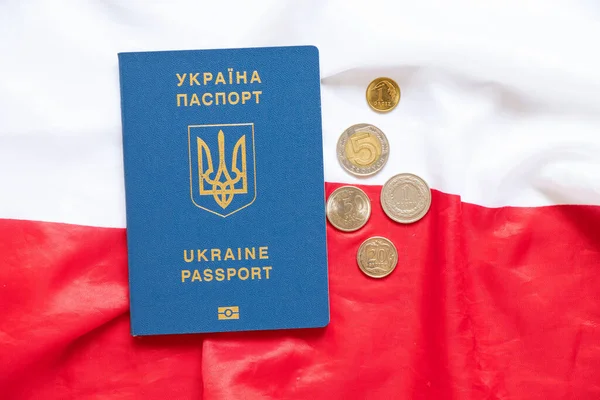 Polish zlotys and a biometric passport of Ukraine lie on the flags of Poland, the finances and economy of Ukraine and Poland, the migration of Ukrainians to Poland due to the war