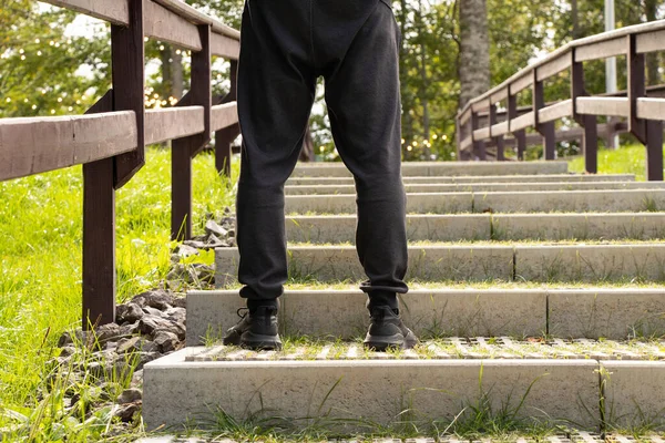 A man climbs the stairs on a sunny day in Ukraine, feet on the steps, climb to success