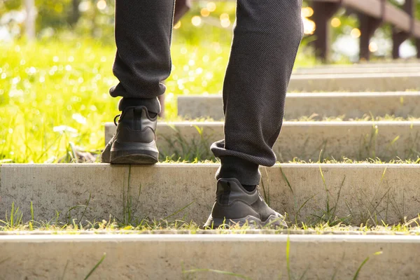 A man climbs the stairs on a sunny day in Ukraine, feet on the steps, climb to success