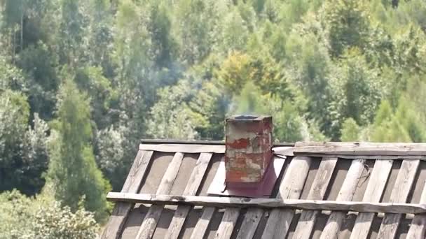 秋に家のストーブを加熱するために ウクライナのカルパティアの山の中で喫煙者と煙と家の屋根 山の中の家 — ストック動画