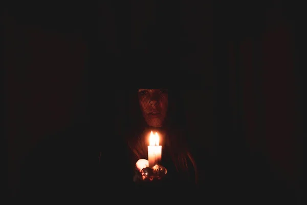 一个戴着女巫帽子的女孩 黑暗中手里拿着蜡烛 黑暗中的女巫和开关的火焰 魔法和魔法 — 图库照片