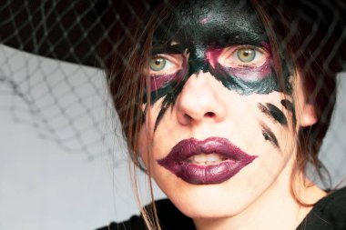 Bir cadının görüntüsü, bir kızın yüzünde cadı makyajı ve bir cadının şapkası, Cadılar Bayramı, bir cadının portresi.