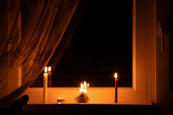 Candles on the window in an apartment in Ukraine, Ukraine without electricity due to the war, an apartment without light, the light of a candle in the window