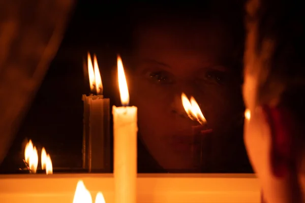 The girl\'s face put candles on the window in an apartment in Ukraine, Ukraine without electricity because of the war, an apartment without light