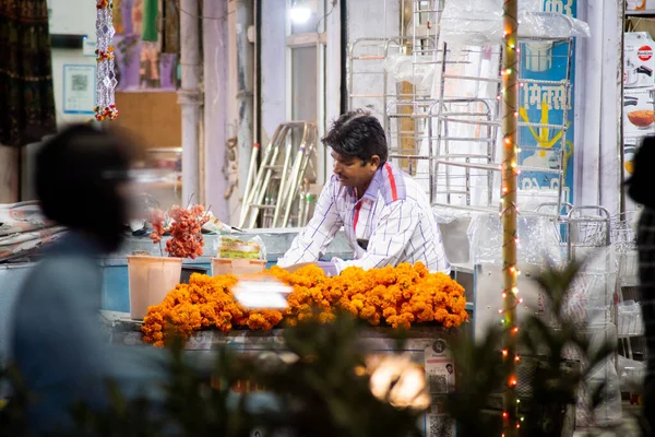 Flower seller with orange gande phool flowers spread out before him selling on the eve of the hindu festival of diwali on side of busy road — Stock Photo, Image