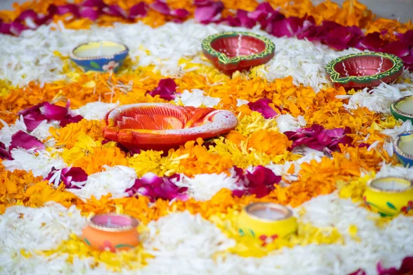 Patrón de Rangoli pookalam hecho de pétalos de flores con lámparas de diya hechas a mano alrededor de él en el suelo para celebraciones religiosas como diwali, Navidad y año nuevo — Foto de Stock