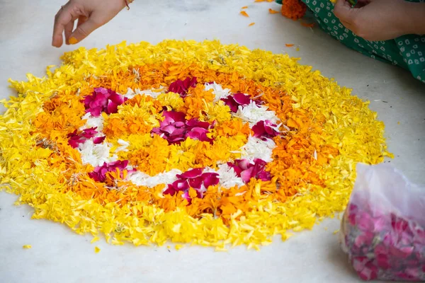 Indiai nő dob marigold jázmin virágok egy rangoli minta a földre, miközben a rangoli diwali, újév vagy esküvői dekoráció részeként a hindu vallás — Stock Fotó