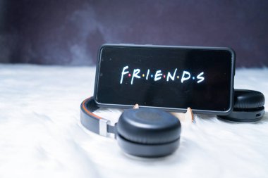 Cep telefonu kürk kar yüzeyine yerleştirilmiş kulaklıklarla ayakta duruyor ve Friends 'in popüler netflix şovunu seyrediyor.