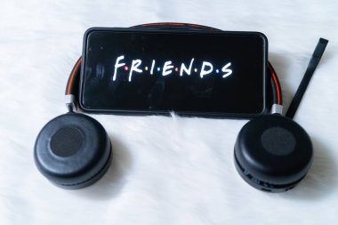 Cep telefonu kürk kar yüzeyine yerleştirilmiş kulaklıklarla ayakta duruyor ve Friends 'in popüler netflix şovunu seyrediyor.