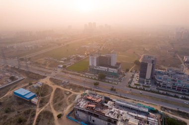 Hava aracı, evleri, ofisleri, alışveriş merkezleri olan bir binanın üzerinden geçerken gün batımının önündeki gökdelenlere doğru ilerlerken, Gurgaon şehrinin boş mahallelerini gösteriyor.