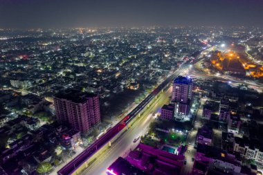 Kalabalık cadde üzerinde yükseltilmiş metro raylarıyla hava aracı görüntüsü. Hyerabad Jaipur Hindistan 'daki trafik gökdelenlerinden gelen ışık yolları var.