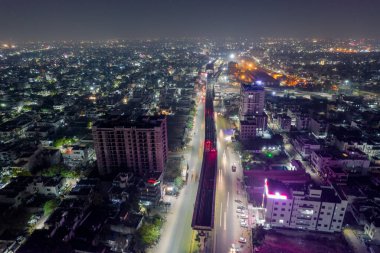 Kalabalık cadde üzerinde yükseltilmiş metro raylarıyla hava aracı görüntüsü. Hyerabad Jaipur Hindistan 'daki trafik gökdelenlerinden gelen ışık yolları var.
