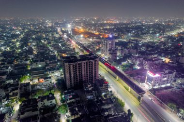 Kalabalık cadde üzerinde yükseltilmiş metro raylarıyla hava aracı görüntüsü. Hyerabad Jaipur Hindistan 'daki trafik gökdelenlerinden gelen ışık yolları var.