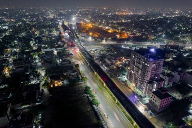 Kalabalık cadde üzerinde yükseltilmiş metro raylarıyla hava aracı görüntüsü. Hyerabad Jaipur Hindistan 'daki trafik gökdelenlerinden gelen ışık yolları var.