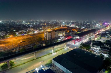 Gökyüzü insansız hava aracı görüntüsü, yüksek metro istasyonunu ve yoğun cadde üzerindeki trafik ve şehir manzarasını gösteriyor. Gurgaon, Jaipur Hindistan 'da