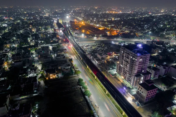 ハイエラバード・ジャイプール・インディア側の交通高層ビルからの光の道で忙しい通りの上に高架地下鉄の線路で撮影された空中ドローン — ストック写真