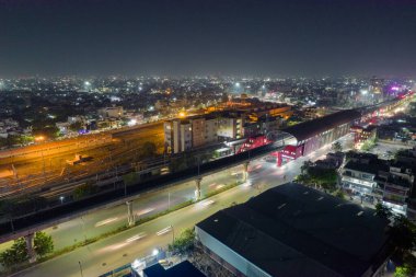 Tren kalkış yapan yüksek metro istasyonu ve yoğun cadde ve avlu üzerindeki ışık yolları Hint şehirlerinin hızla geliştiğini gösteriyor.