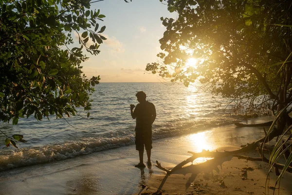 Disparo del hombre disparando la puesta de sol del amanecer en el horizonte silueta contra el resplandor anaranjado y las olas chapoteantes del mar andaman en swaraj dweep havelock en la India — Foto de Stock