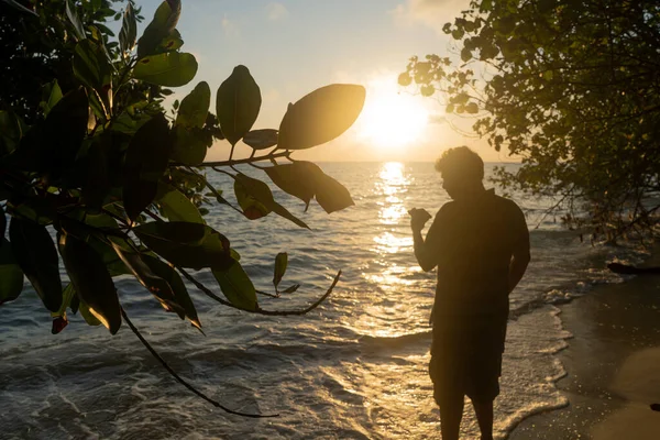 Disparo del hombre disparando la puesta de sol del amanecer en el horizonte silueta contra el resplandor anaranjado y las olas chapoteantes del mar andaman en swaraj dweep havelock en la India — Foto de Stock