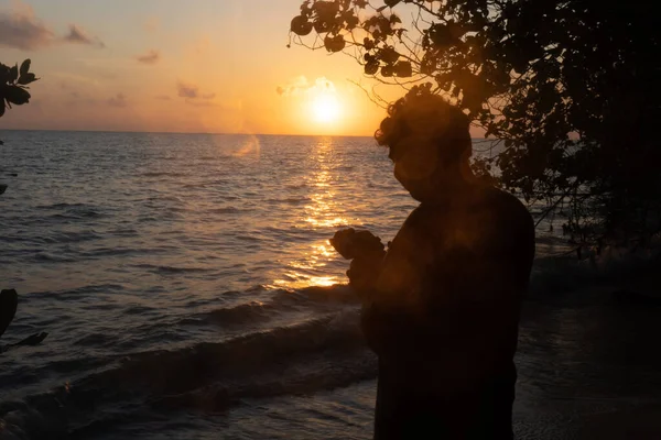 Shot of man shooting the sunrise sunset on horizon silhouetted against the orange glow and the lapping waves of andaman sea in swaraj dweep havelock in India — 스톡 사진