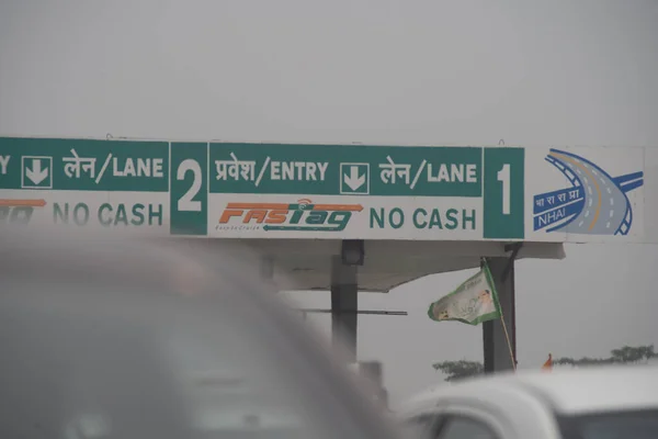 Перевантажені автомобілі затору перед митною кабіною показують нову платіжну систему на основі RFID FASTag разом з логотипом для національних органів дорожнього руху Індії NHAI — стокове фото