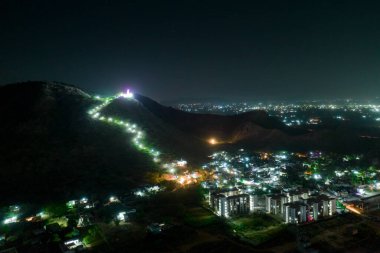 Şehir ışıklarını gösteren ve Hindistan 'ın güzelliğini gösteren Rajasthan Jaipur' daki tepenin tepesindeki tapınağa kadar uzanan gece çekimleri.