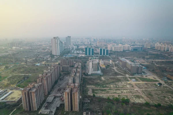 Hava aracı, evleri, ofisleri, alışveriş merkezleri olan bir binanın üzerinden geçerken gün batımının önündeki gökdelenlere doğru ilerlerken, Gurgaon şehrinin boş mahallelerini gösteriyor.