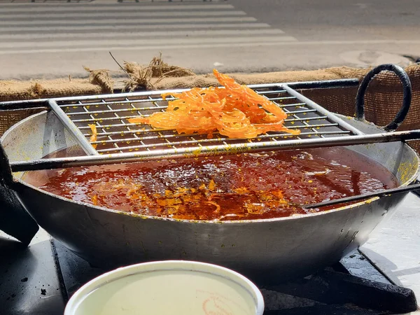 Close up of shop cook deep frying many jalebi in boiling oil allowing it to rest on wire mesh making streetfood snack that is popular throughout rajasthan jaipur India for its sweet flavor — Stock Photo, Image