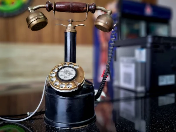 Vintage antique phone with long neck to hold receiver and rotary dial placed at an office restaurant counter in India — стоковое фото