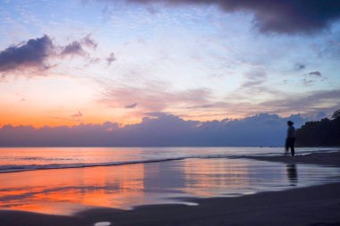 Siluet plajdaki bulanık insanları bulanıklaştırdı. Güzel turuncu, mavi bulutlu günbatımı Kalapathar plajında.