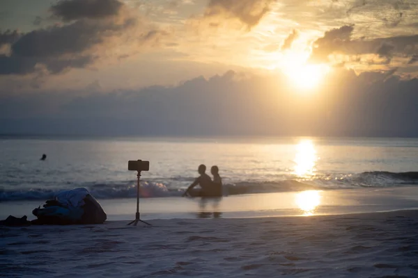 Pareja sentada en la playa con teléfono en trípode tomando fotos mostrando nómadas digitales, influencers y viajeros profesionales en andaman island India —  Fotos de Stock