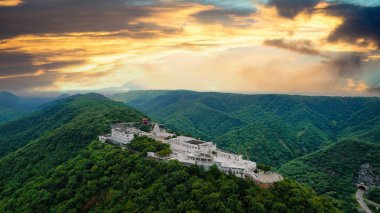 Hava aracının yörüngedeki görüntüsü, Agra Jaipur yolu üzerindeki ünlü Chulgiri Jain tapınağını gösteriyor. Ghat ki guni tüneli, yemyeşil aravalli dağlarının tepesinde beyaz bina.