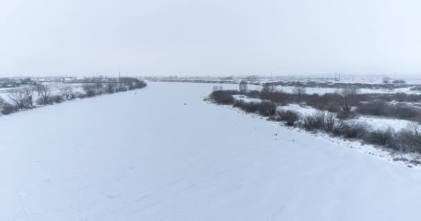 Letecké video rybářů na ledě zamrzlé řeky v zatažený den v prosinci