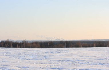 Güneşli bir kış gününde şehrin arkasındaki dumanlı bacalara bakın.