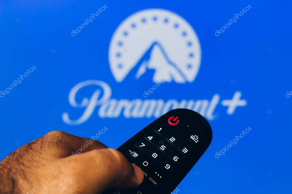 February 21, 2022, Brazil. In this photo illustration a close-up of a hand holding a TV remote control seen displayed in front of the Paramount + (Plus) logo