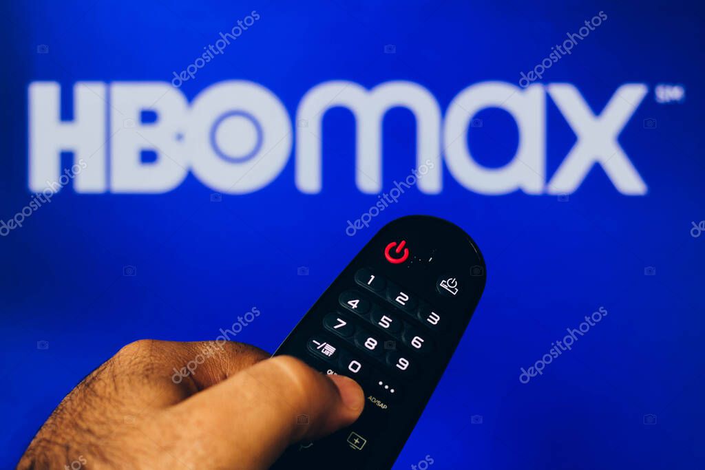 February 21, 2022, Brazil. In this photo illustration a close-up of a hand holding a TV remote control seen displayed in front of the HBO Max logo