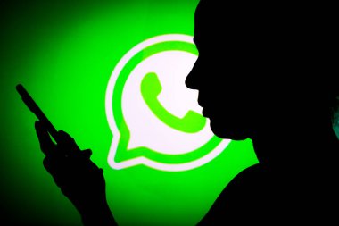 14 Mart 2022, Brezilya. Bu resimde WhatsApp logosu arka planda cep telefonu tutan siluet bir kadının logosu görülüyor.