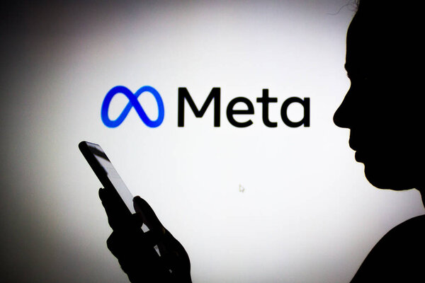 March 14, 2022, Brazil. In this photo illustration the Meta Platforms logo seen in the background of a silhouette woman holding a mobile phone