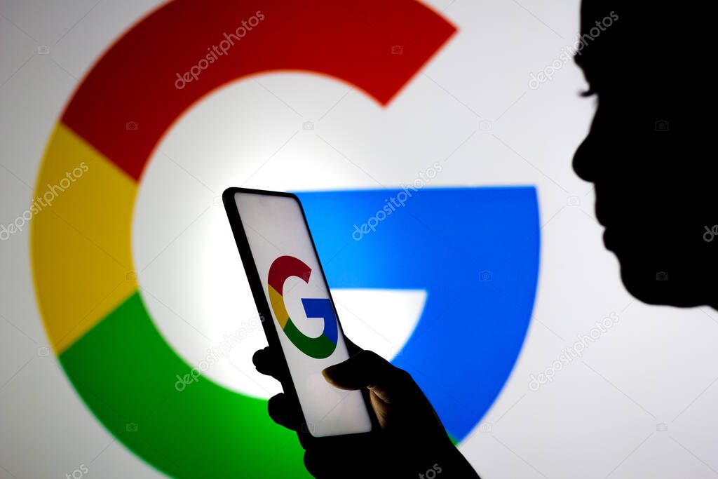 March 19, 2022, Brazil. In this photo illustration, a woman holds a smartphone with the Google logo displayed on the screen and on the background