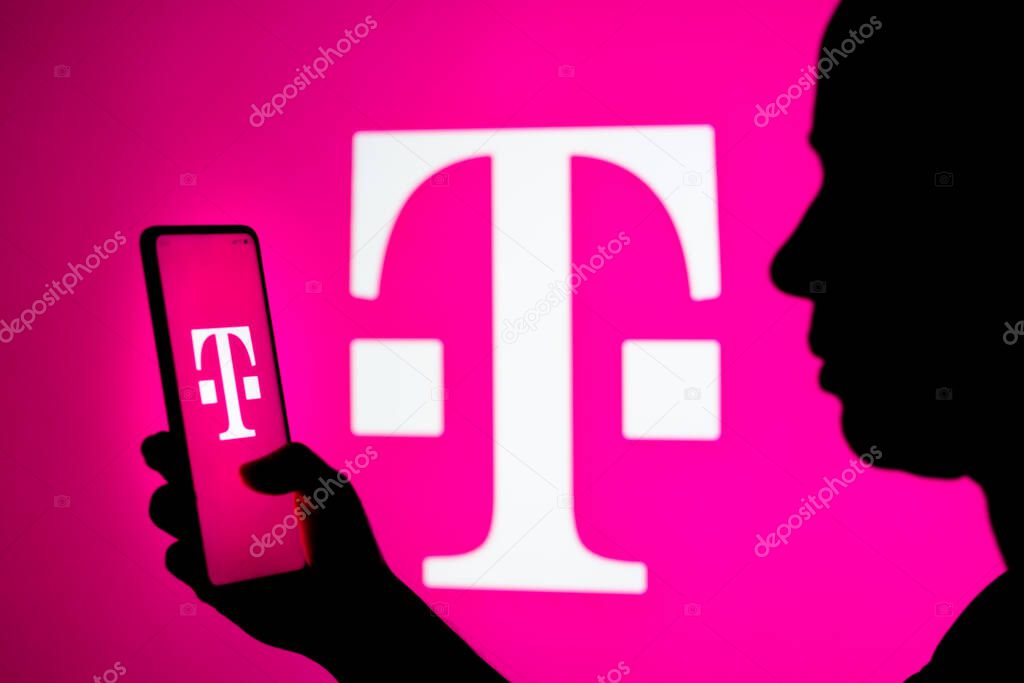 March 22, 2022, Brazil. In this photo illustration, a woman's silhouette holds a smartphone with the T-Mobile US (Deutsche Telekom) logo in the background
