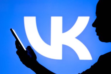 23 Mart 2022, Brezilya. Bu resimde, bir kadının siluetinde arka planda VKontakte (VK) logosu bulunan bir akıllı telefon bulunuyor. Saint Petersburg, Rusya merkezli, Facebook 'a eşdeğer bir sosyal ağ.