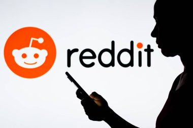 28 Mart 2022, Brezilya. Bu resimde, bir kadının silueti arkasında Reddit logosu olan bir akıllı telefon tutuyor.