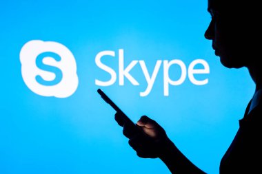 28 Mart 2022, Brezilya. Bu resimde, bir kadının siluetinde arka planda Skype logosu olan bir akıllı telefon var.