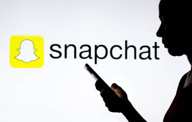 28 Mart 2022, Brezilya. Bu resimde, bir kadının siluetinde arka planda Snapchat logosu olan bir akıllı telefon var.